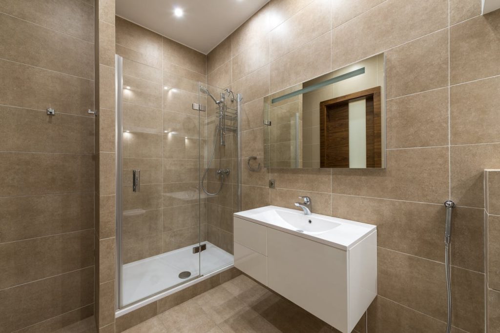 zipwp-image-7166939 Elegantly designed modern bathroom featuring a glass shower, wall mirror, and large ceramic tiles.